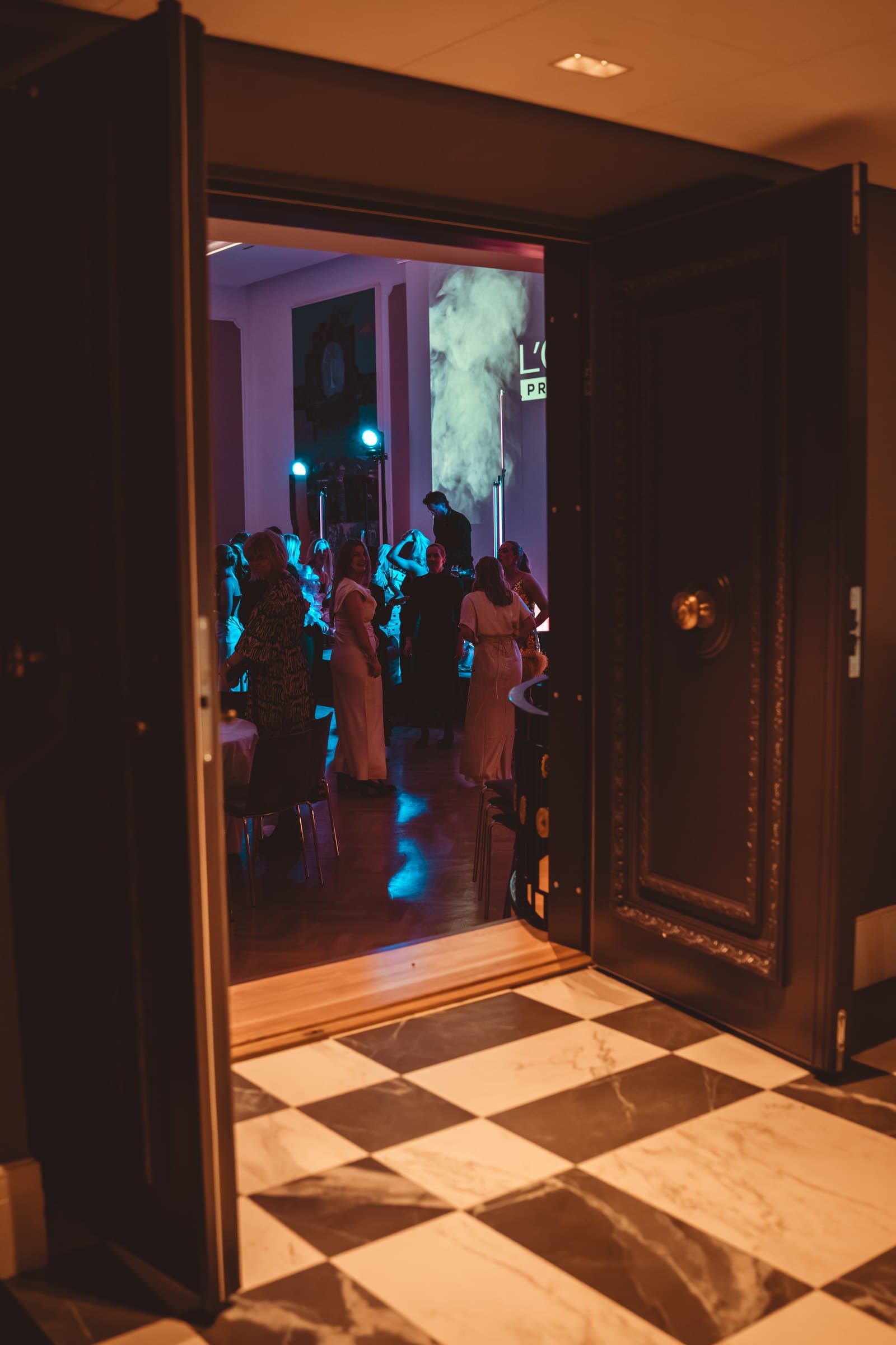 Gjester på dansegulvet sett gjennom en åpen dør under en bedriftsfest for L'Oréal Professionnel