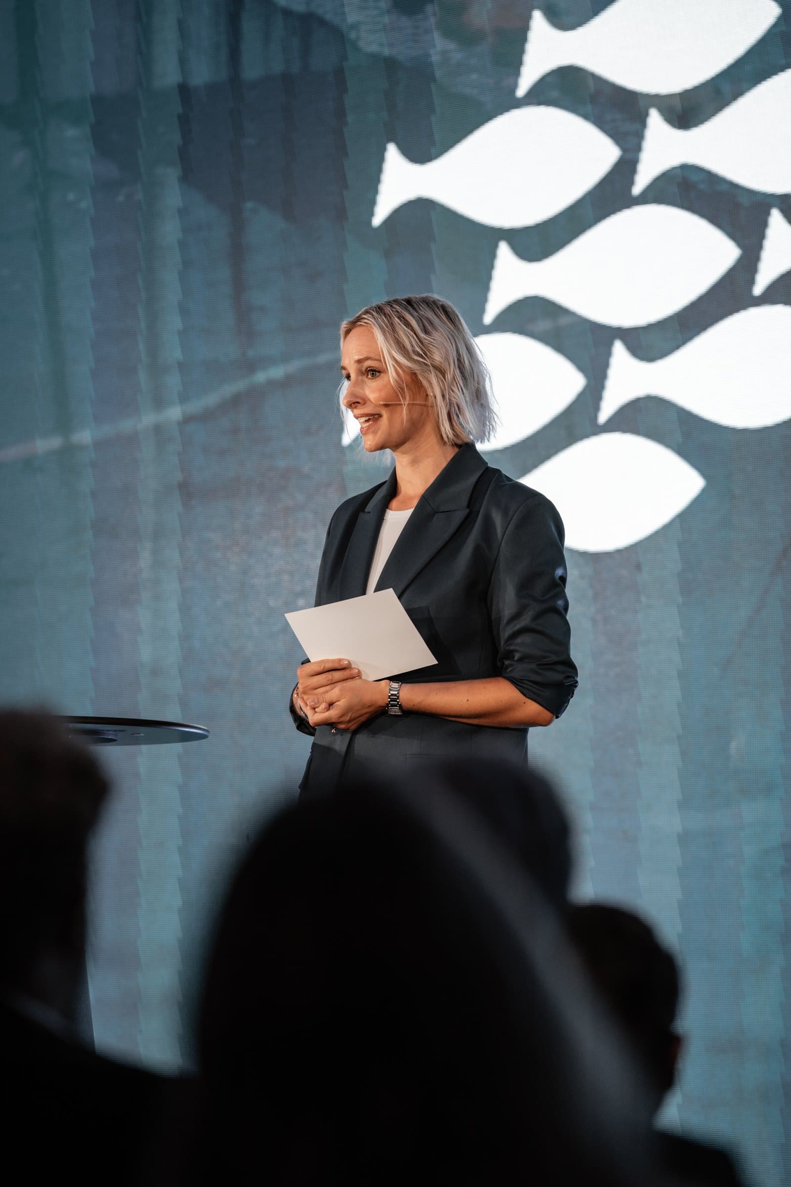Konferansier på scenen under NOR-FISHING, med publikum i forgrunnen
