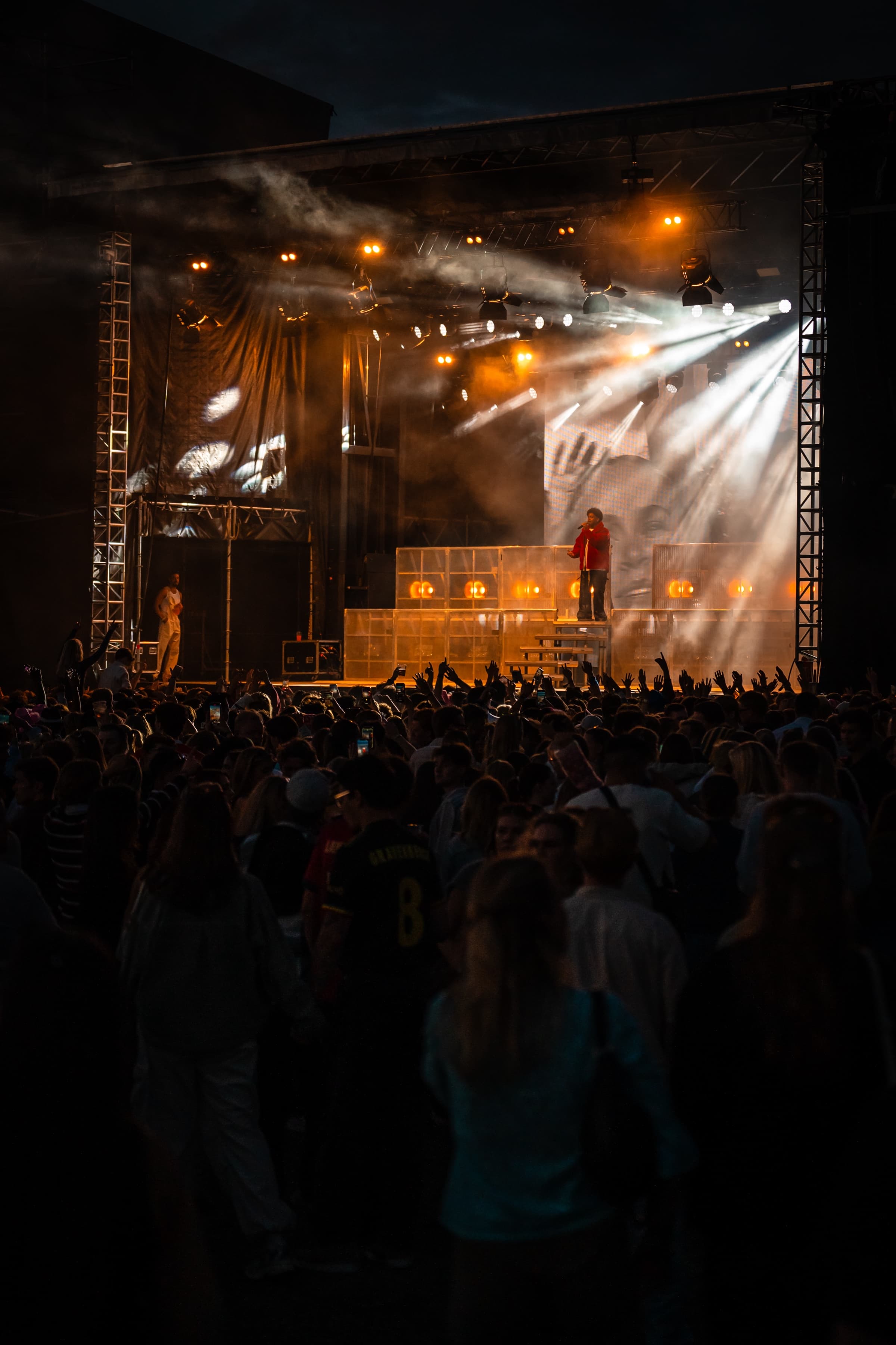 Konsertscene med kraftig lysrigg og røyk, sett fra folkemengden under et konsertoppdrag